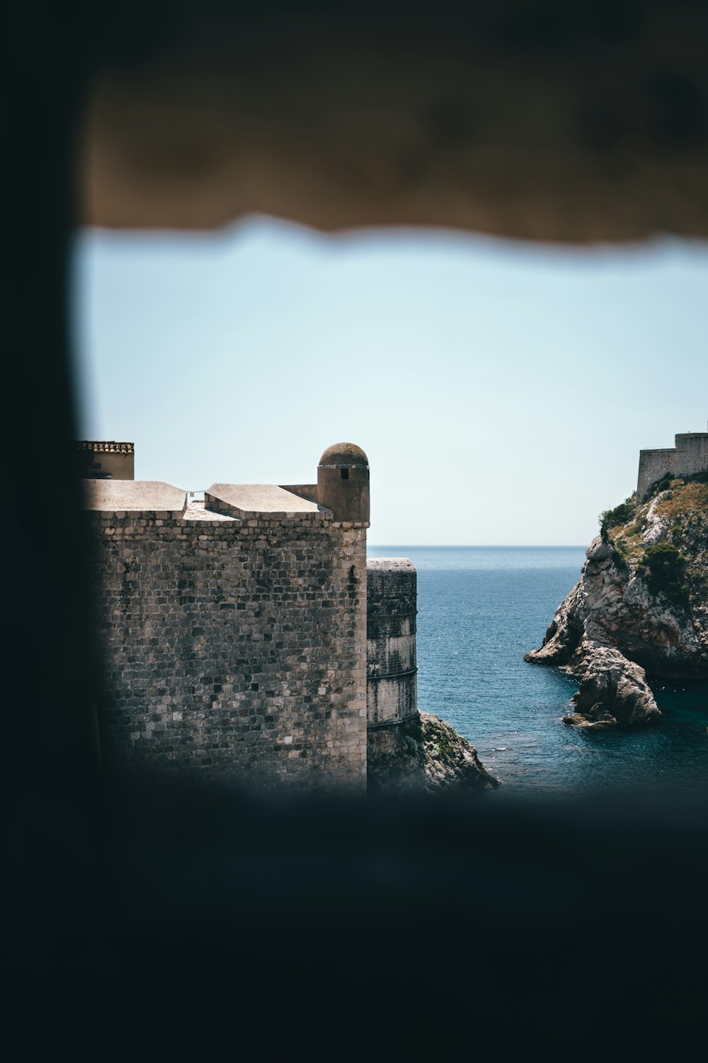 brown concrete building on cliff by the sea during daytime