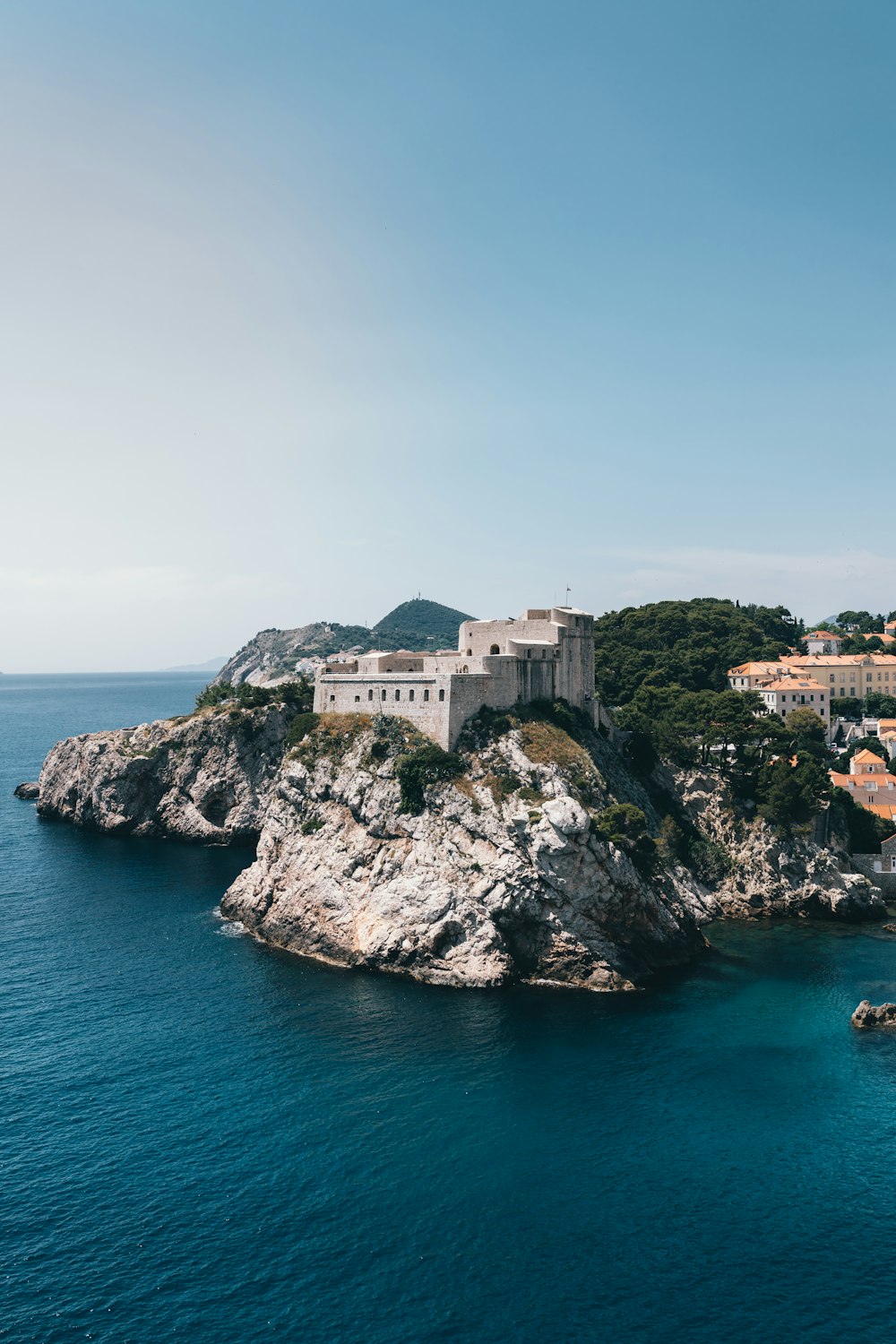 white concrete building on cliff near body of water during daytime