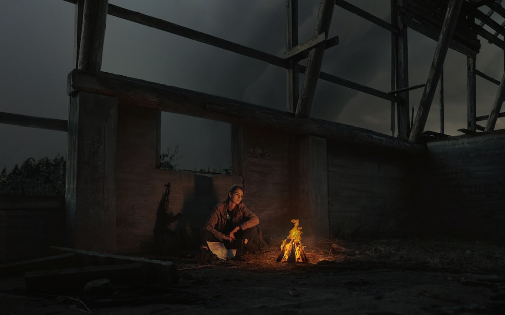 man in brown jacket sitting on chair near bonfire