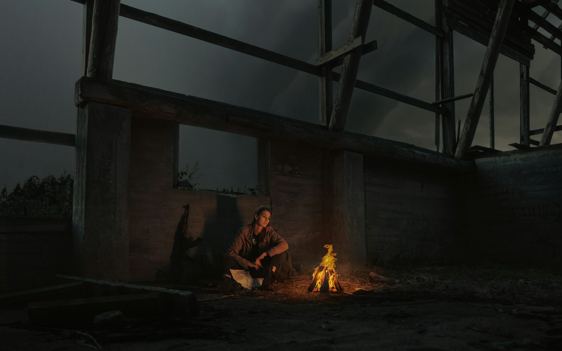 man in brown jacket sitting on chair near bonfire