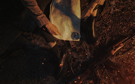 Person using a map for survival sitting by a campfire.