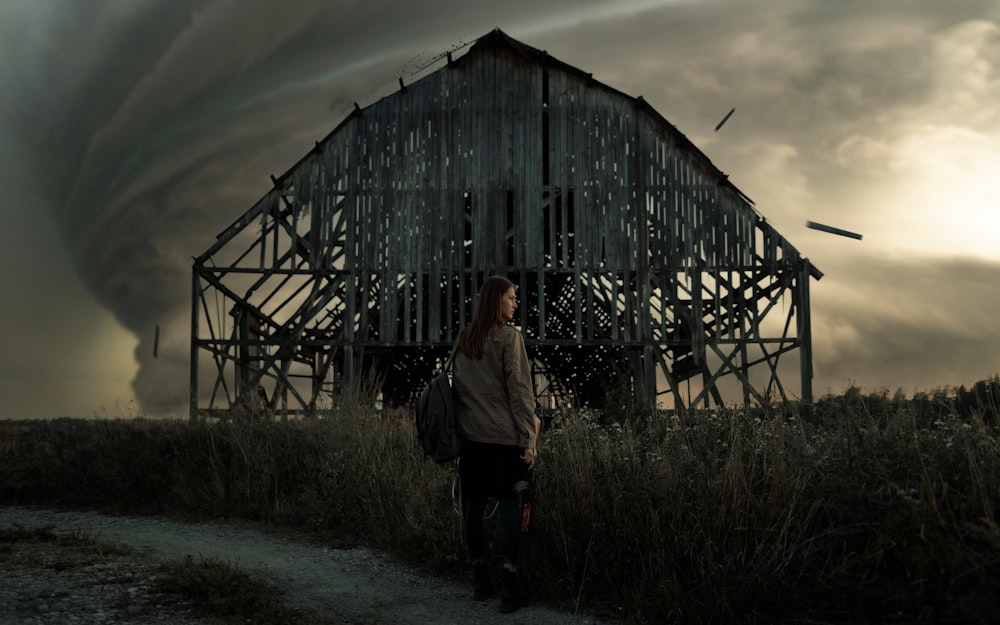 man in white long sleeve shirt standing beside brown wooden barn