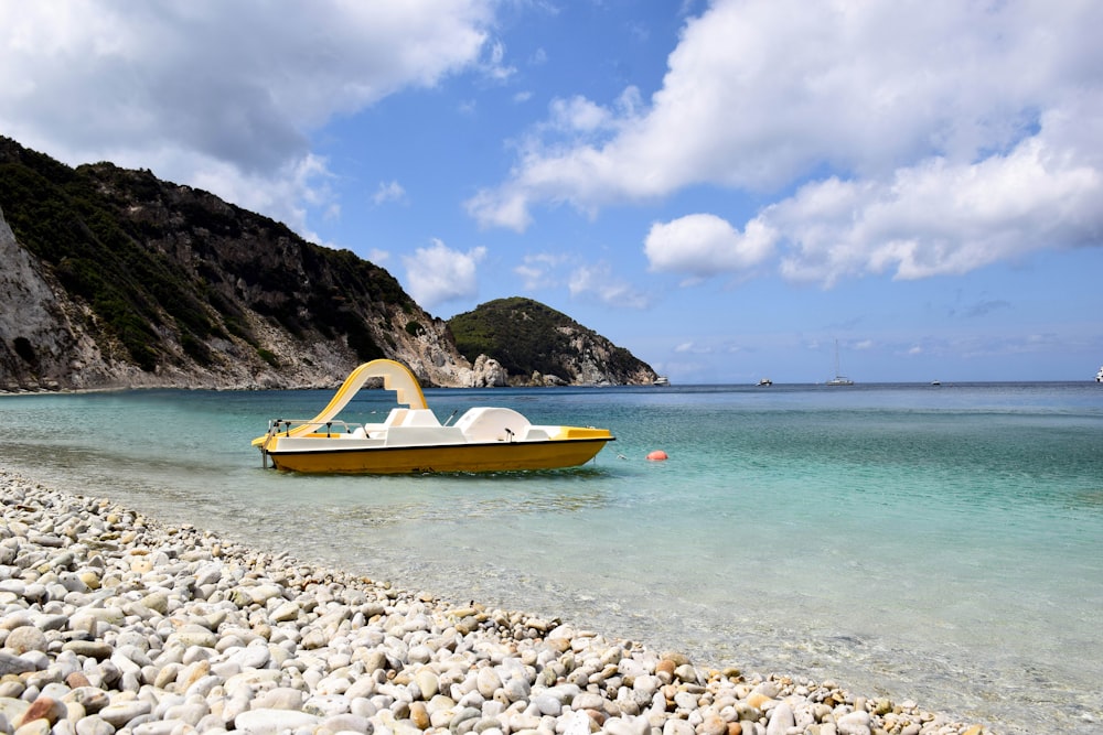 kayak jaune et bleu sur le rivage rocheux blanc pendant la journée