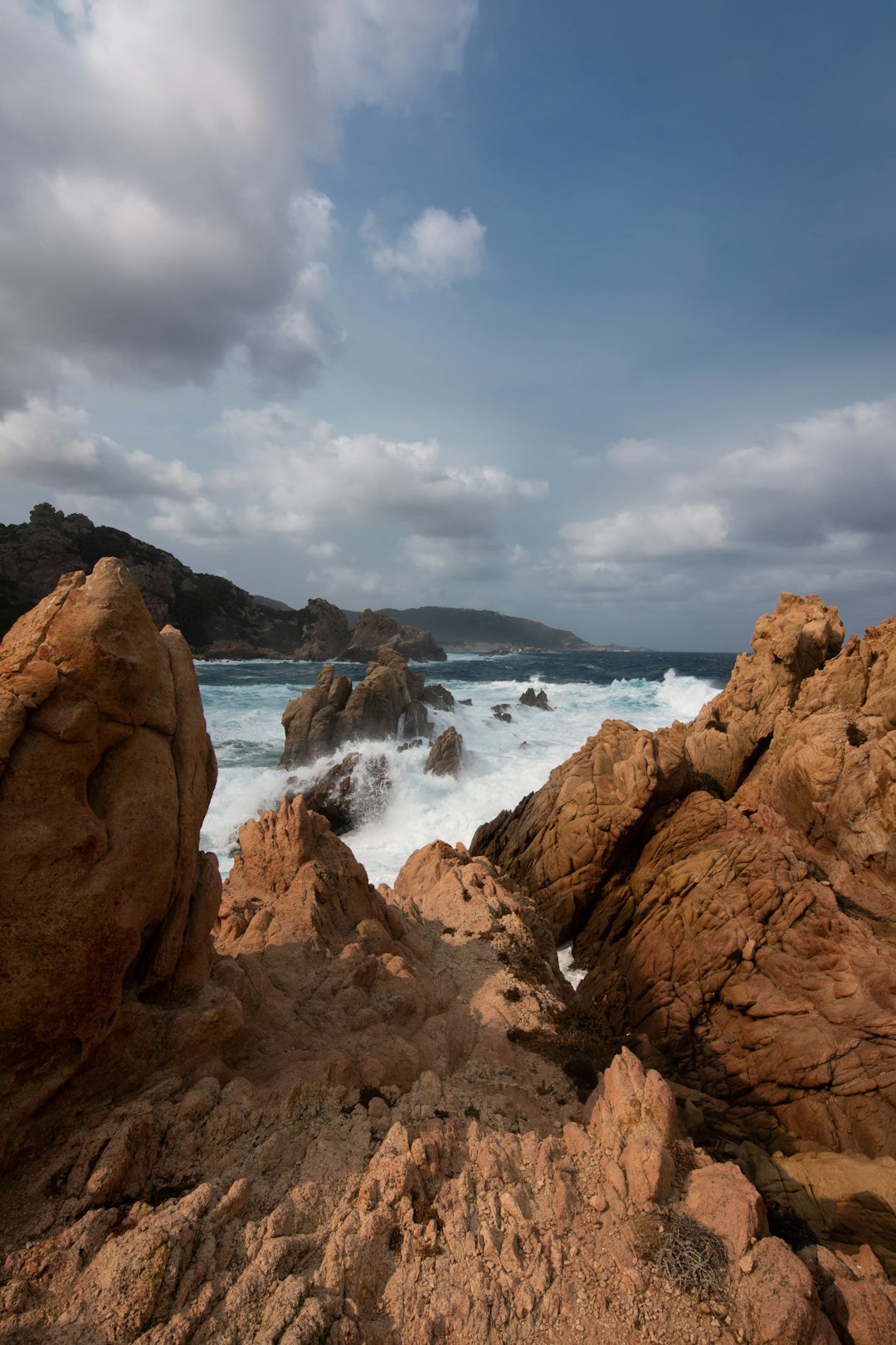 brown rock formation near body of water under cloudy sky during daytime