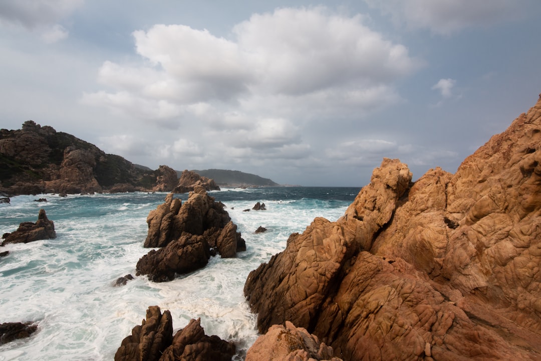 brown rock formation on sea under white clouds during daytime