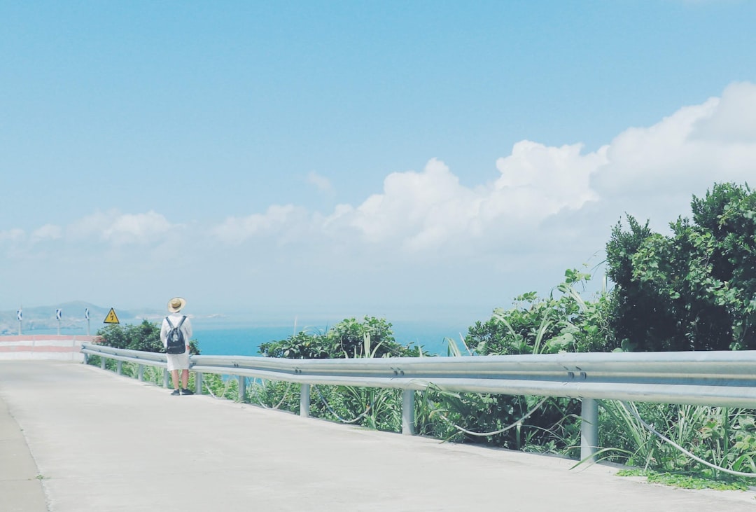 woman in white shirt and blue denim jeans walking on white wooden dock during daytime