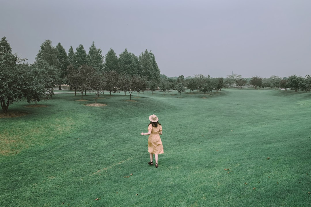 girl in pink bikini running on green grass field during daytime