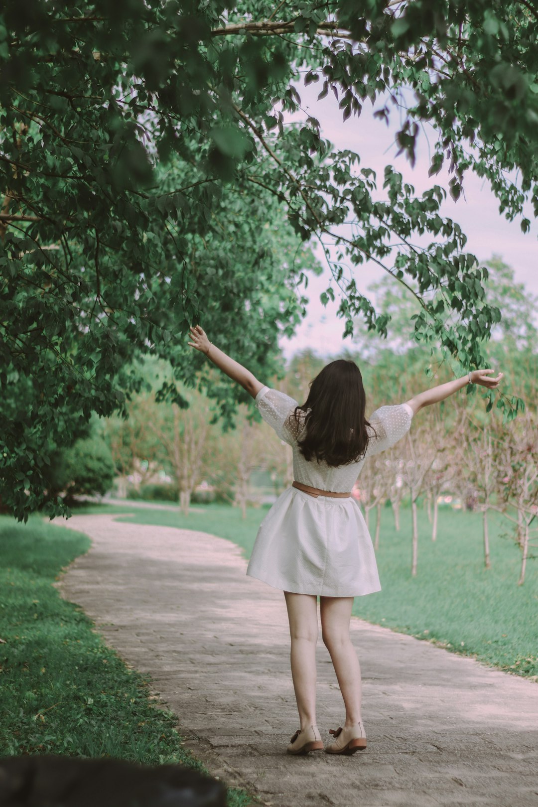 girl in white dress standing on brown pathway