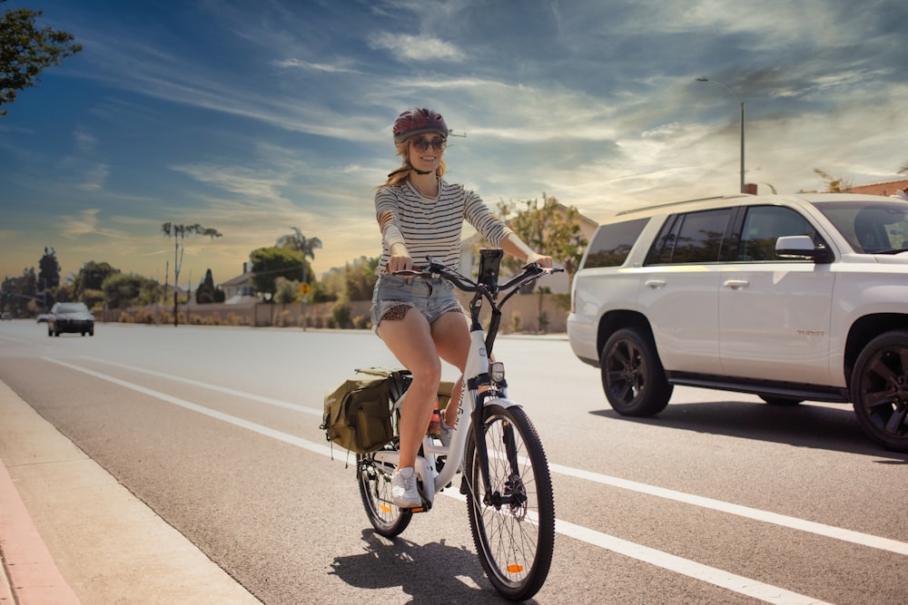 woman in white and black striped long sleeve shirt riding on bicycle on road during daytime