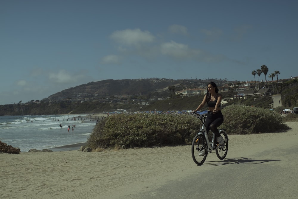 woman in black tank top riding bicycle on beach during daytime