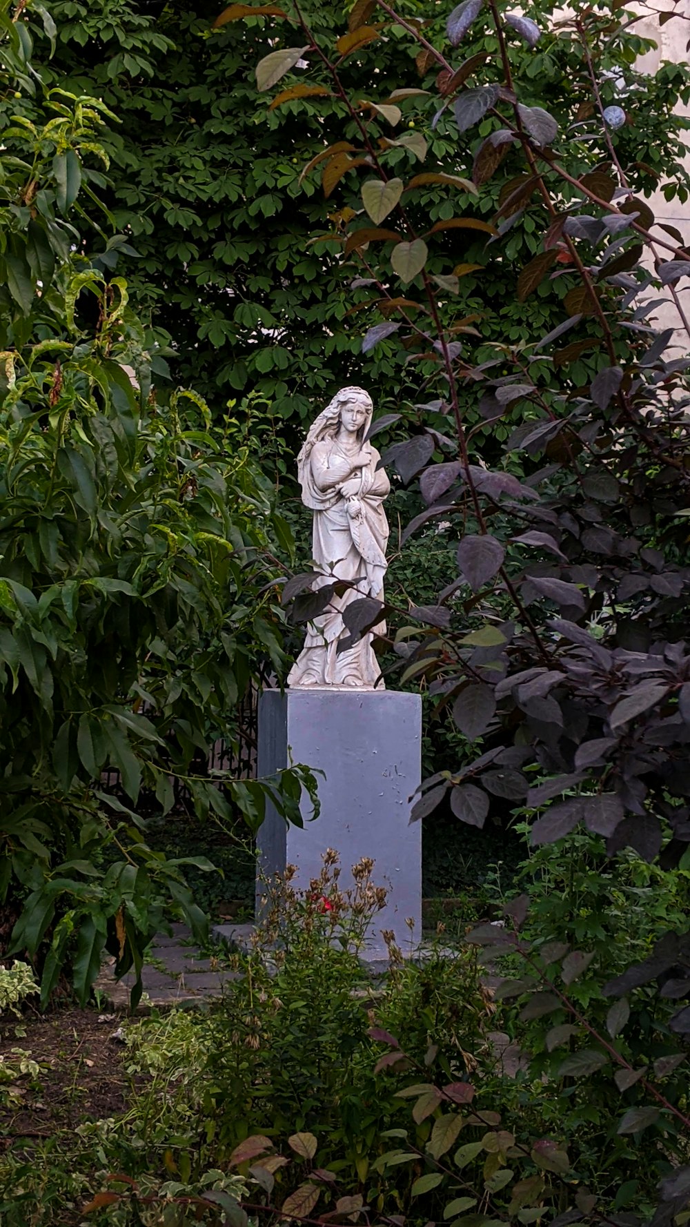 녹색 식물 근처의 드레스 동상에 여자