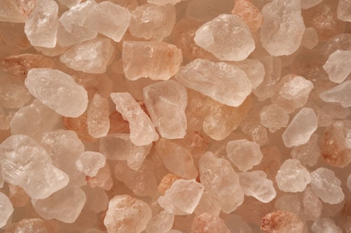 A collection of roughly shaped, semi-transparent pink and white crystals closely clustered together.
