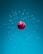 A red cricket ball is floating in mid-air surrounded by shattered glass fragments suspended in a blue environment. The ball's stitching and color are prominent, creating a striking contrast against the cool background.