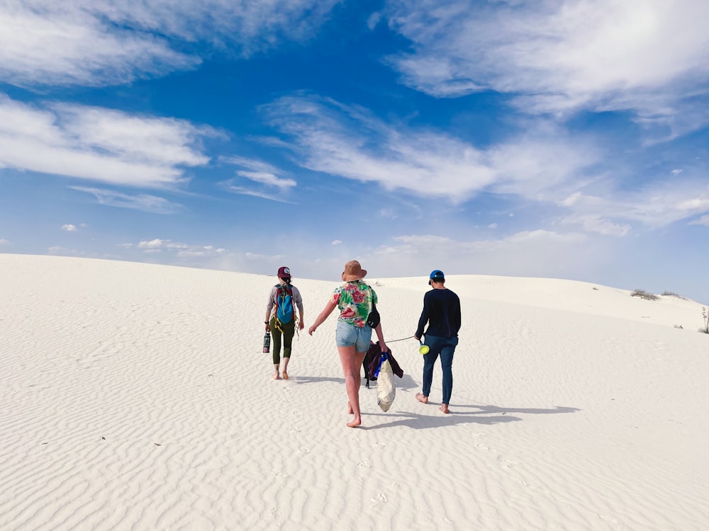 3 women walking on sand during daytime