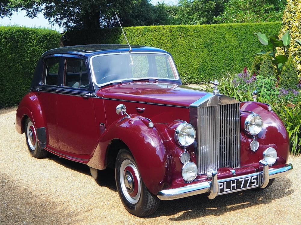 red vintage car on green grass field during daytime