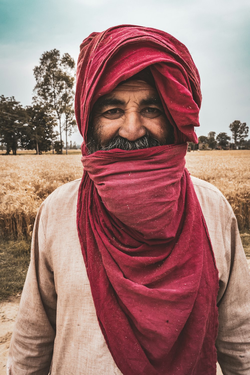 woman in red hijab standing on brown field during daytime