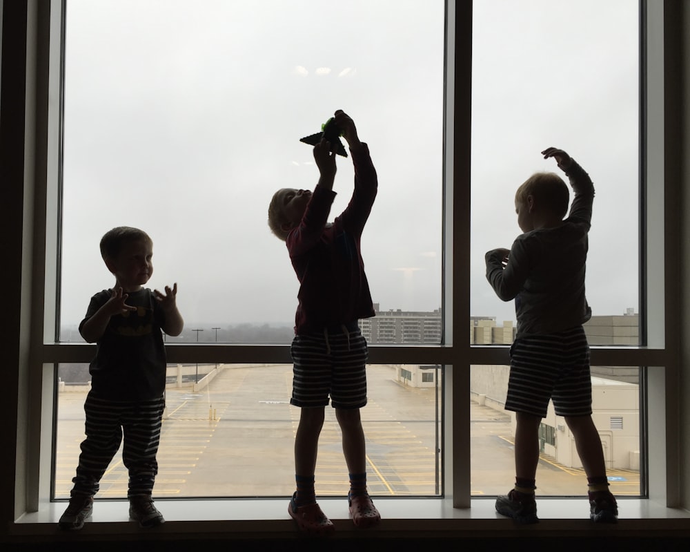 3 boys standing on brown wooden floor during daytime