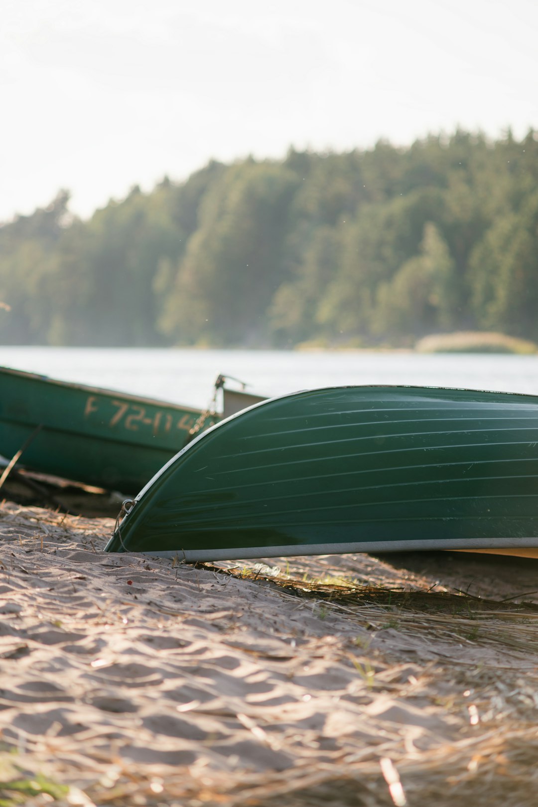 green boat on brown sand near body of water during daytime