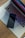 A sleek smartphone is placed on the touchpad of a laptop with a colorful backlit keyboard. The laptop rests on a wooden surface, and the screen displays a gradient of colors.