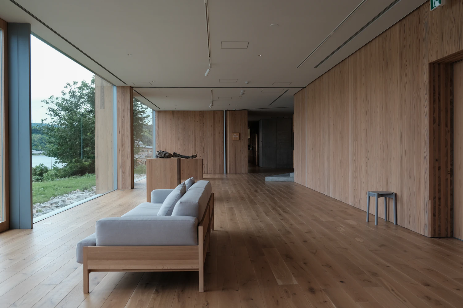 A long timber-lined living room with the sliding door open to the shore