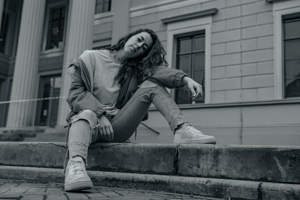 woman in jacket and pants sitting on concrete stairs