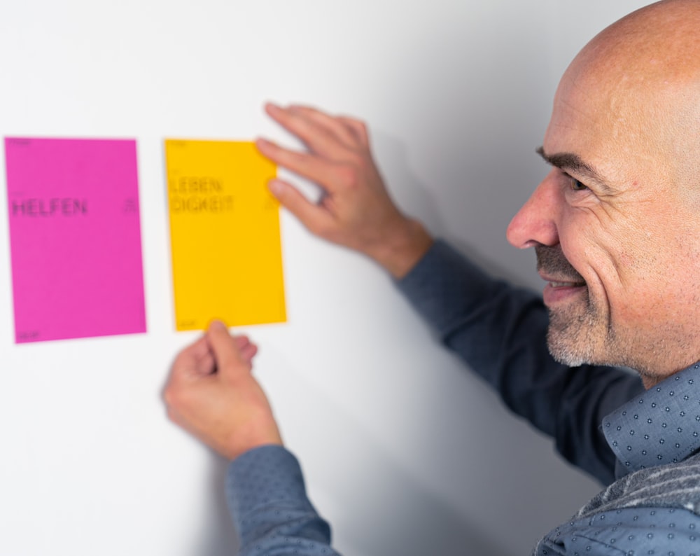 man in gray long sleeve shirt holding yellow sticky note