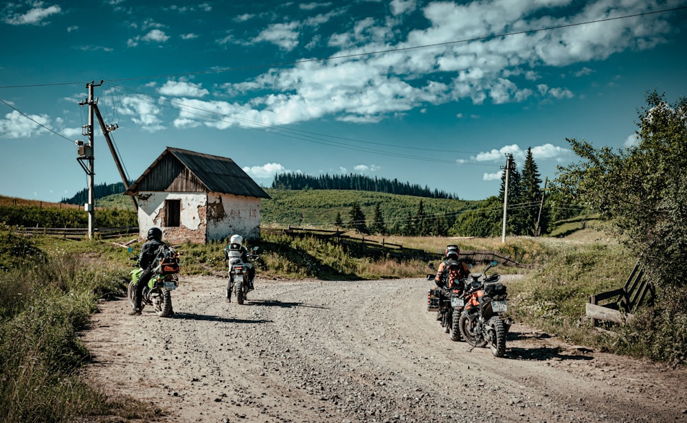 Menschen, die tagsüber auf der Straße in der Nähe von grünen Bäumen und braunem Holzhaus Motorrad fahren