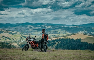 man in black jacket riding black motorcycle on green grass field during daytime