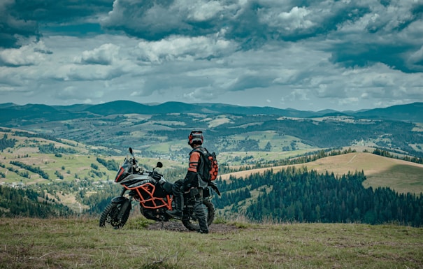 man in black jacket riding black motorcycle on green grass field during daytime
