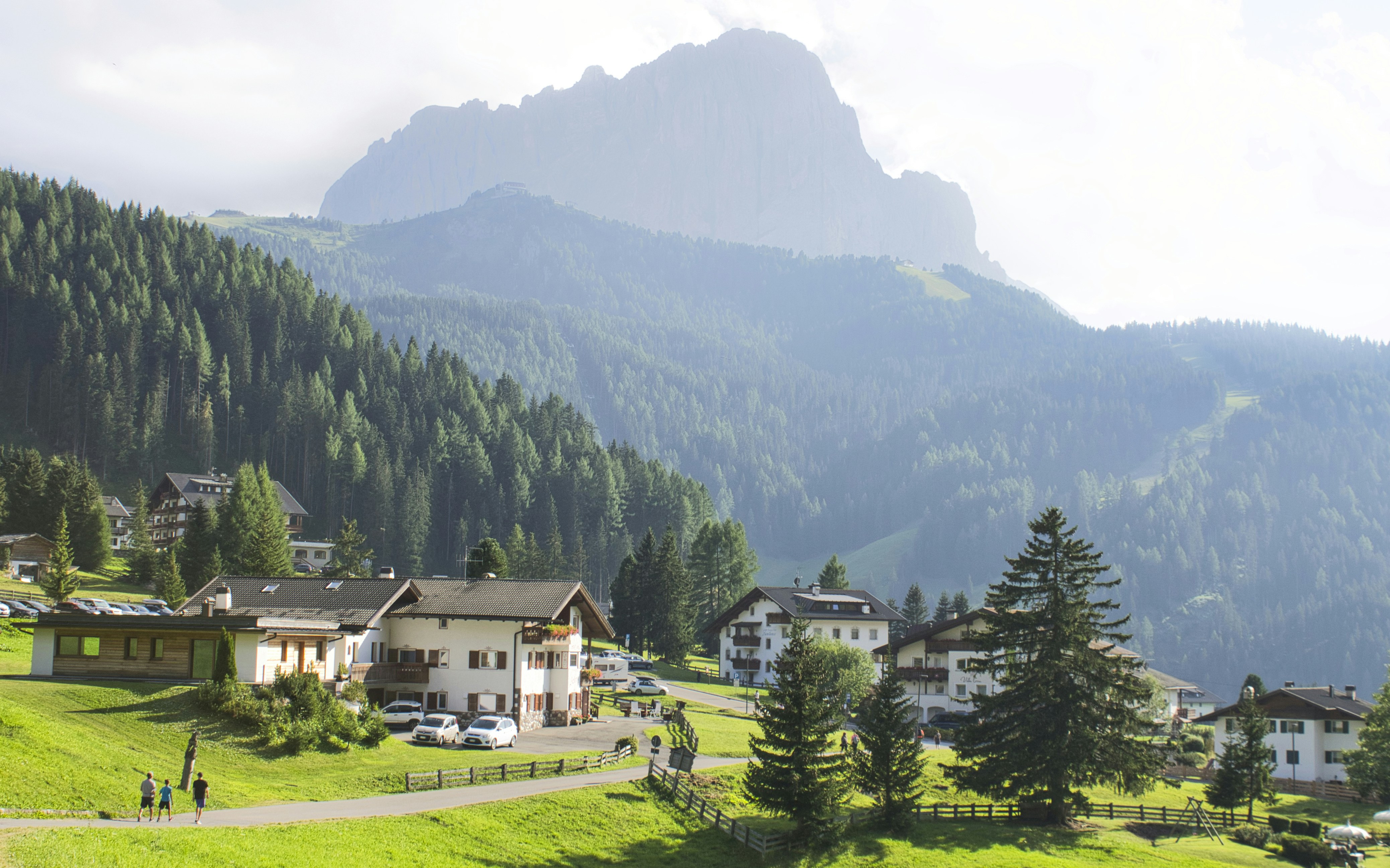 white and brown house near green trees and mountain during daytime