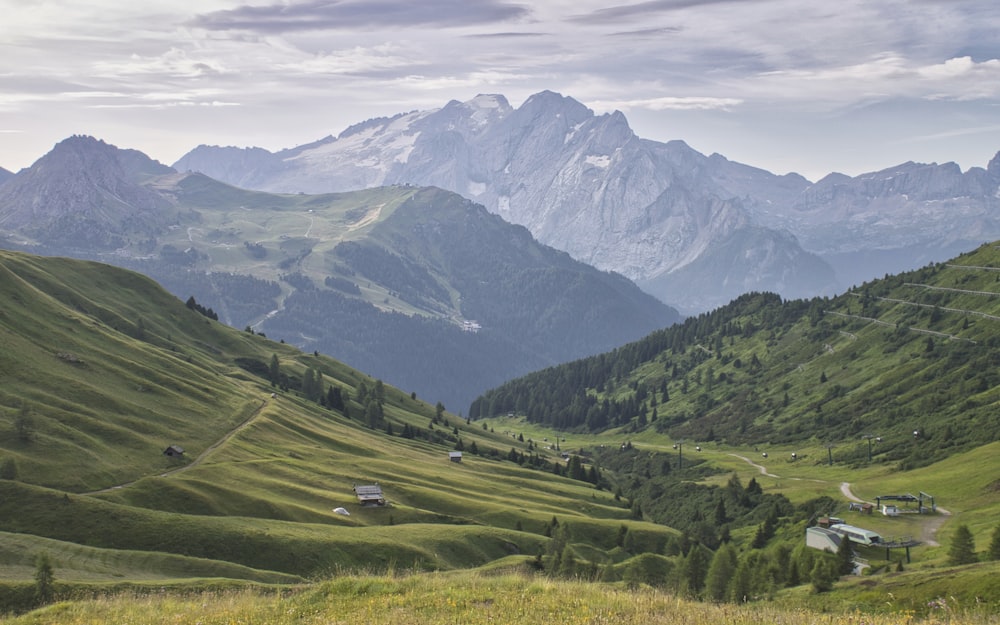 campo di erba verde vicino alla montagna sotto il cielo blu durante il giorno