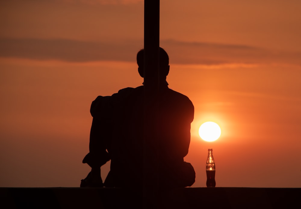 Silueta de hombre y mujer sentados en banco de hormigón durante la puesta del sol