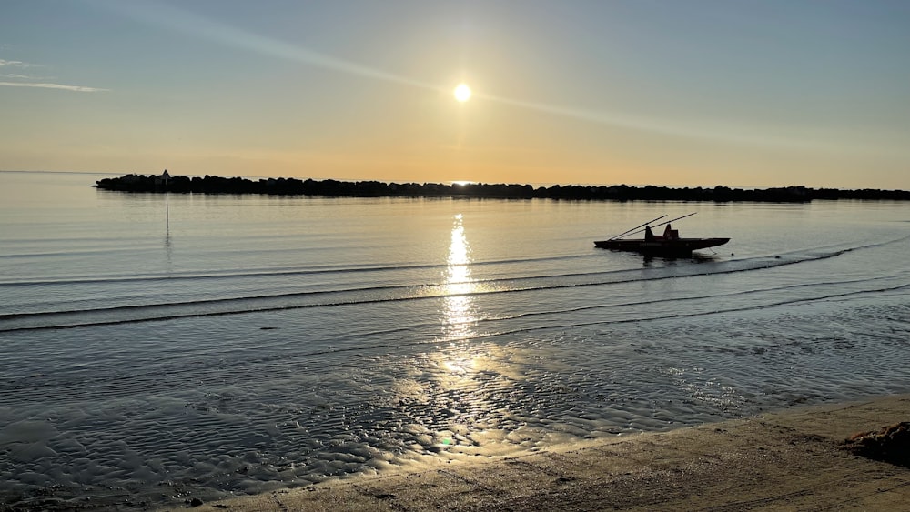 silhouette of boat on sea during sunset