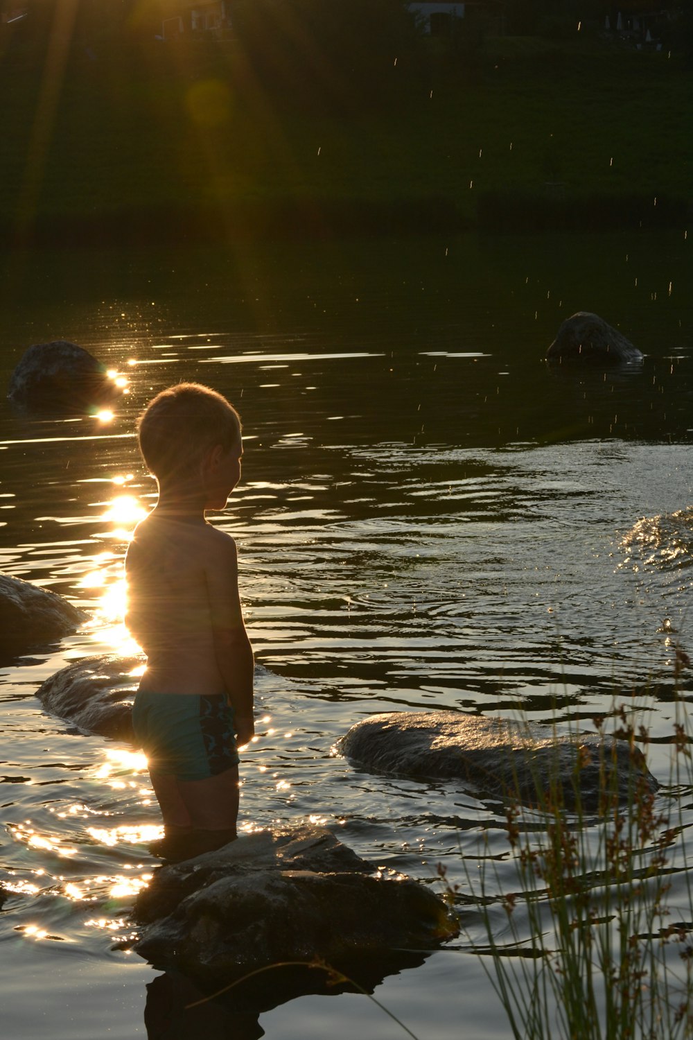 topless boy in blue shorts standing on water during daytime