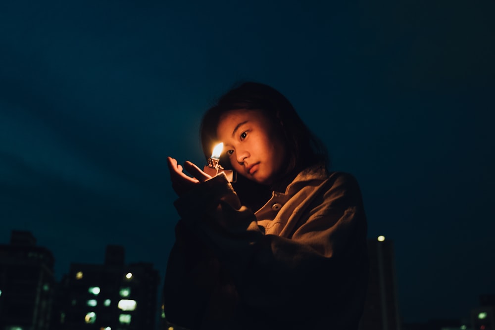 woman in brown hoodie holding lighted cigarette stick
