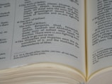 An open book displaying text in black font on cream-colored pages. The text includes headings and paragraphs in a serif typeface, and there are visible margins and page edges.