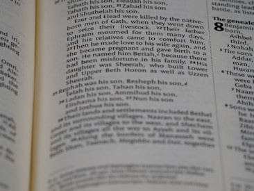 A close-up view of a page from a book with text describing genealogy. The text includes names and familial relationships written in a traditional serif font. The layout is typical of a religious or historical text with numbers denoting verses or sections.