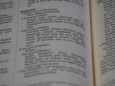 A page from a book with text referring to genealogies, specifically mentioning names such as Benjamin, Bela, Beker, and their sons. The text is formatted in two columns with bold headings for sections.