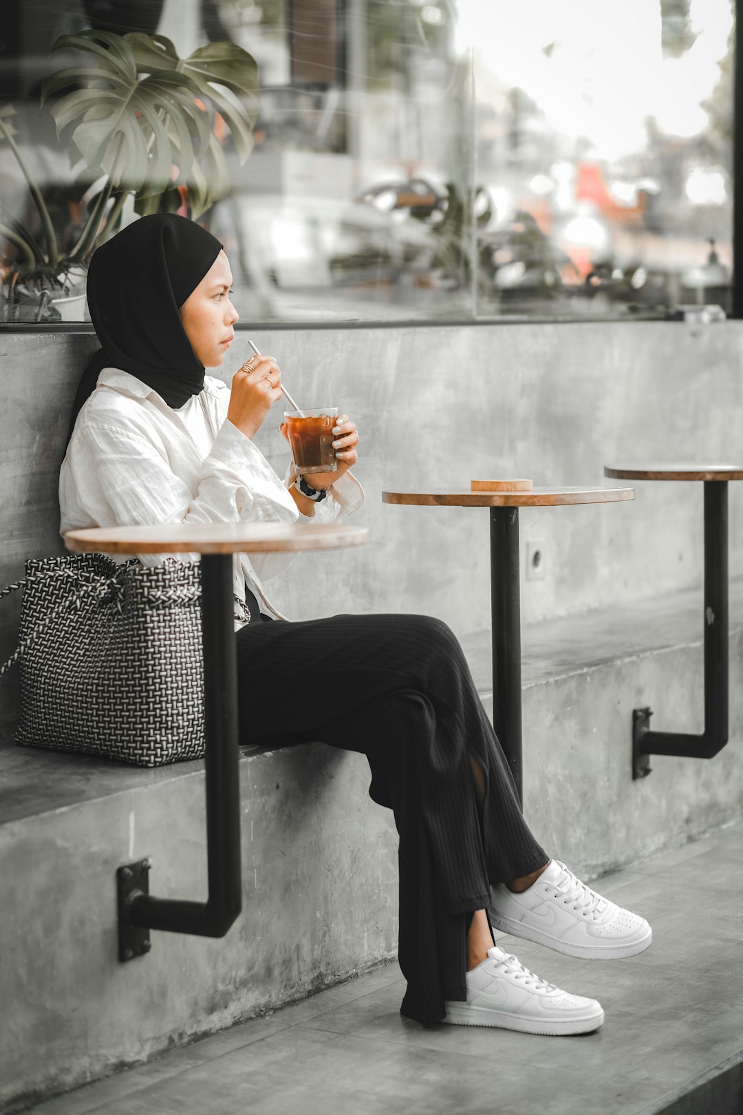 woman in white long sleeve shirt and black pants sitting on black metal bench