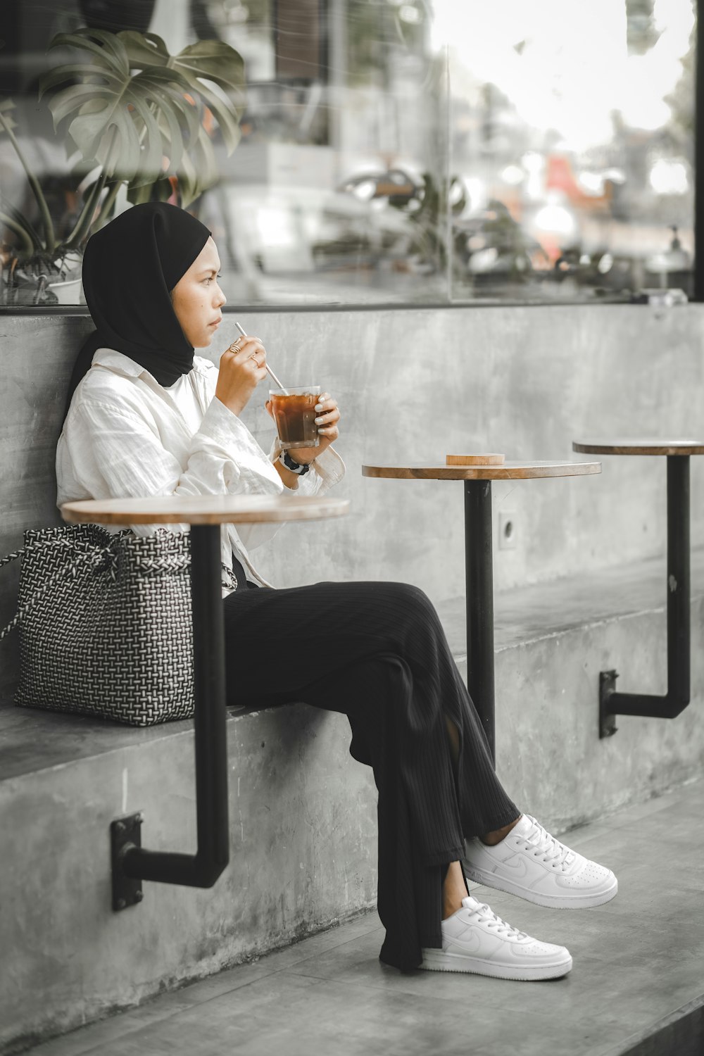 woman in white long sleeve shirt and black pants sitting on black metal bench
