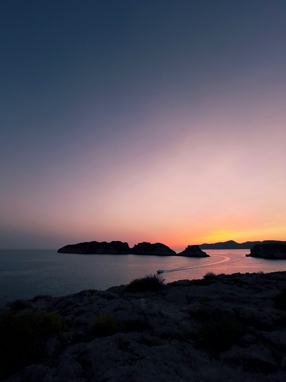 Silueta de la montaña cerca del cuerpo de agua durante la puesta del sol