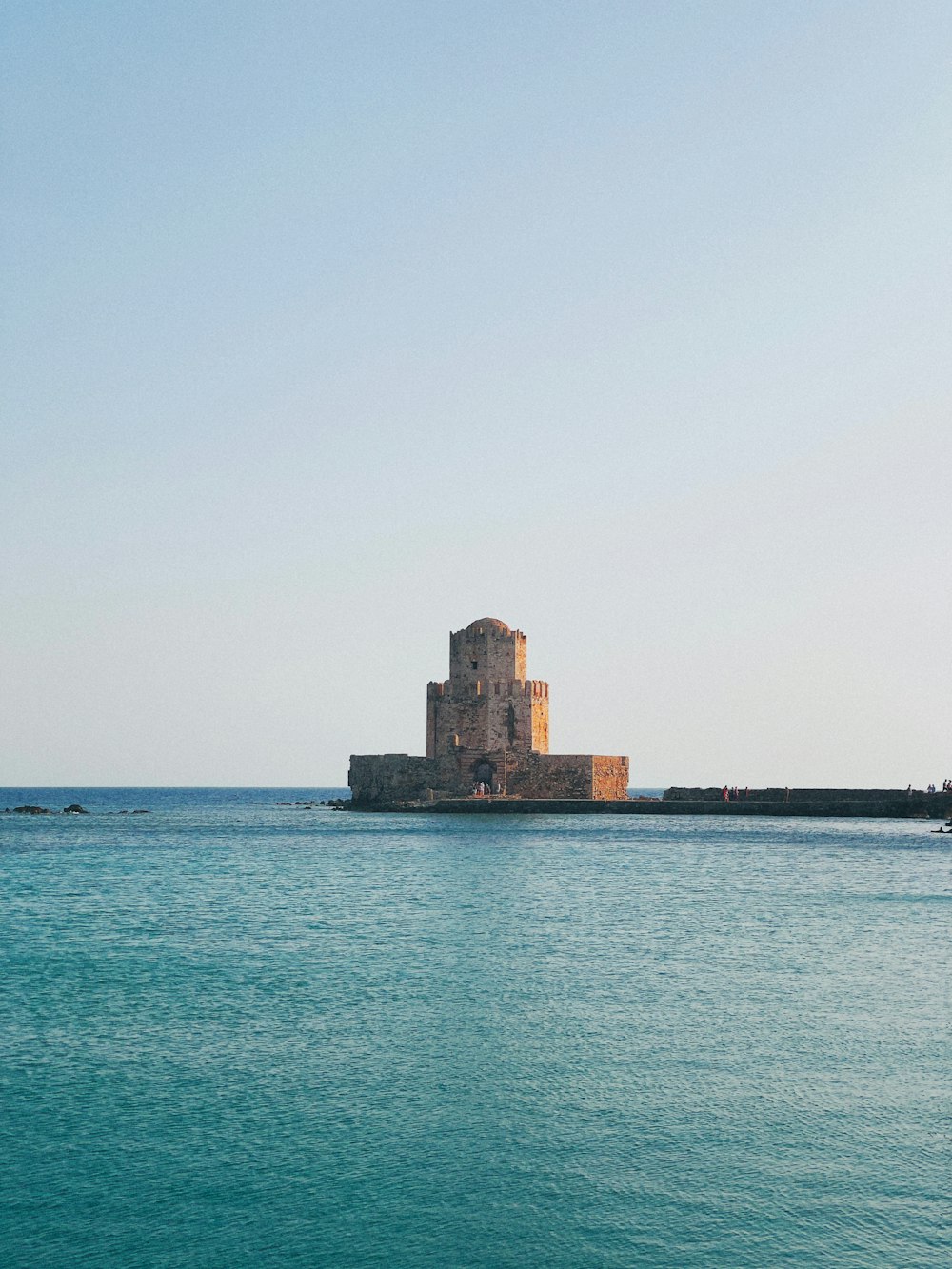 brown concrete building near sea under white sky during daytime