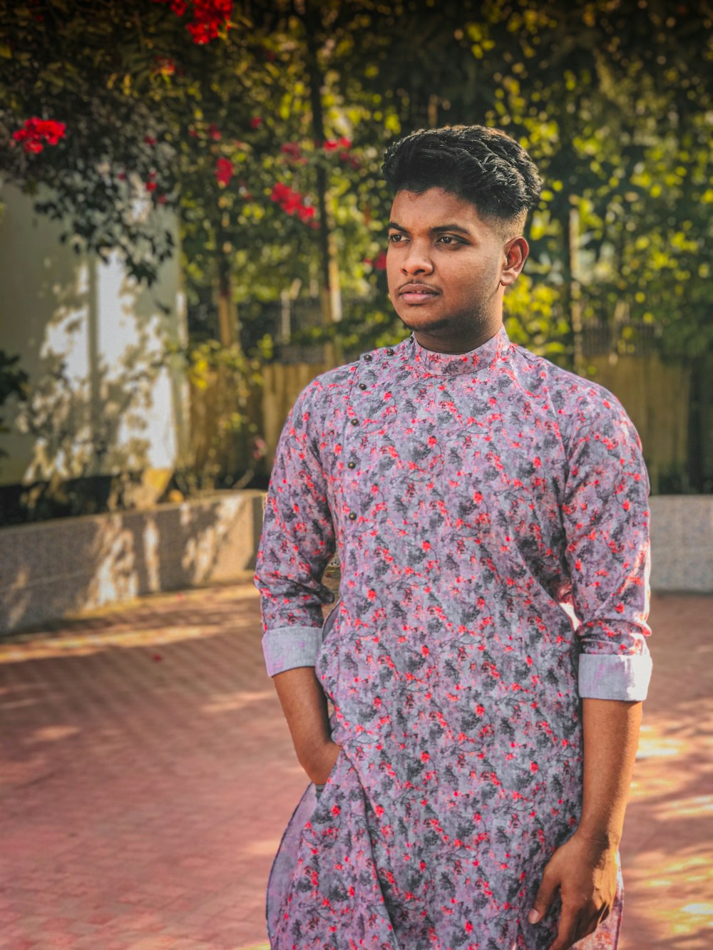 man in red and white floral dress shirt standing on brown brick pathway