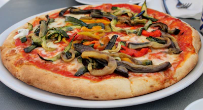 A vibrant plate of freshly baked pizza topped with colorful vegetables and melted cheese.