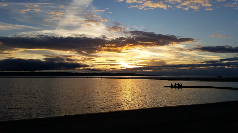 silhouette of people on boat on sea during sunset