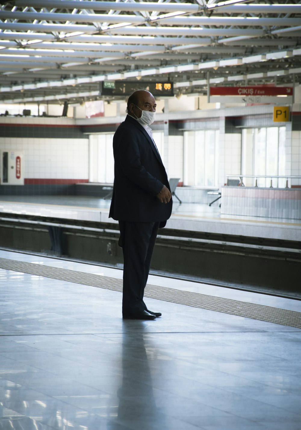 man in black suit walking on white floor tiles