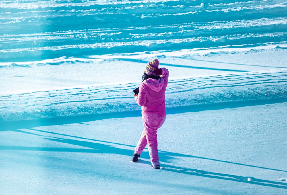 woman in pink hoodie and pants standing on snow covered ground during daytime