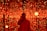 A person is standing in front of a backdrop filled with numerous glowing red lights. The lights create a mesmerizing and immersive environment. The person is holding a camera, capturing the scene or possibly taking a selfie.