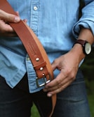 A woven fabric belt in earthy tones, casually draped over a denim jacket.