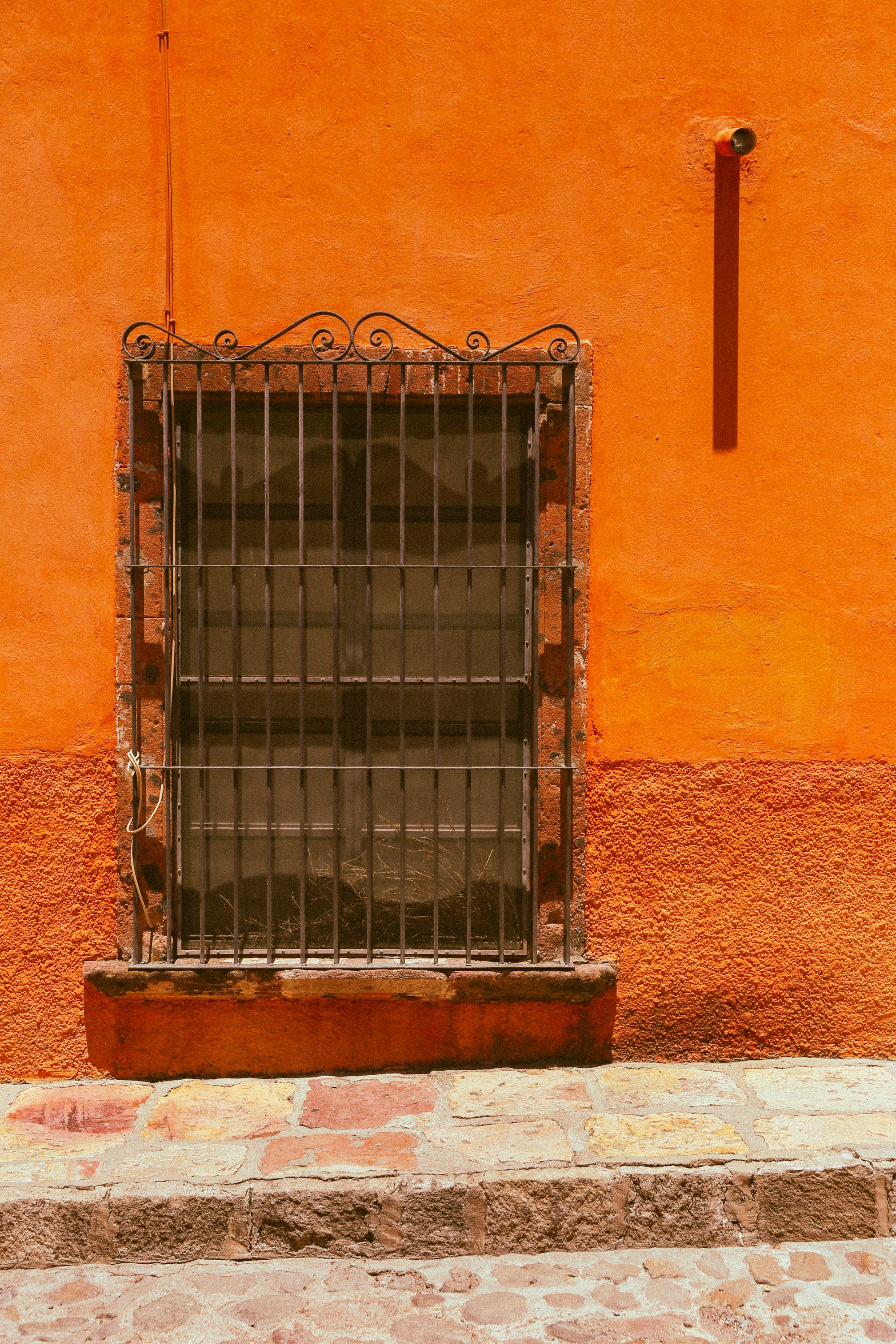 black metal window grill on brown concrete wall